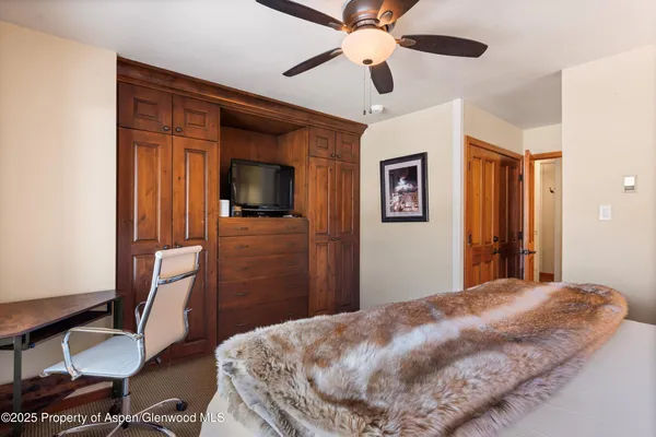 a bedroom with a bed dresser and a flat tv screen