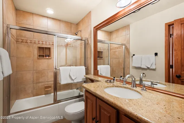a bathroom with a granite countertop sink toilet and shower
