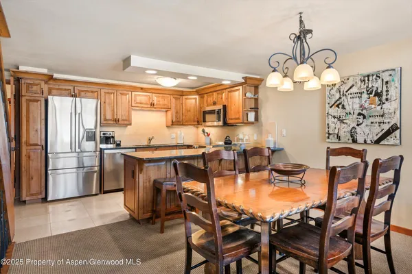 a kitchen with stainless steel appliances granite countertop a table chairs and a refrigerator