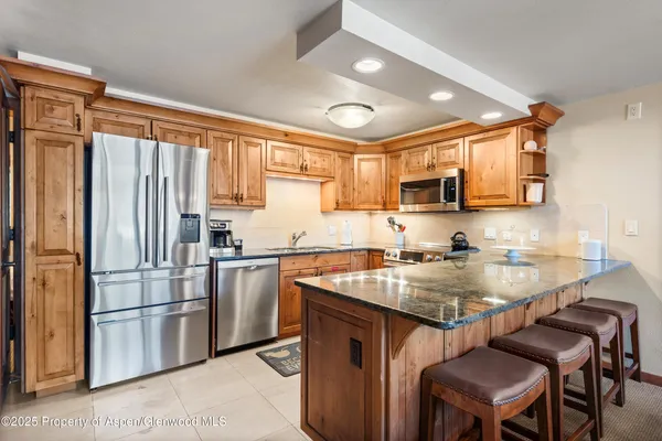 a kitchen with stainless steel appliances granite countertop a sink a stove a refrigerator and cabinets