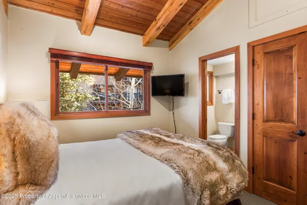a bedroom with a bed and a flat tv screen next to a window
