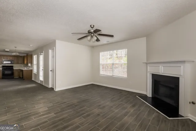 a view of an empty room with a fireplace and a chandelier fan