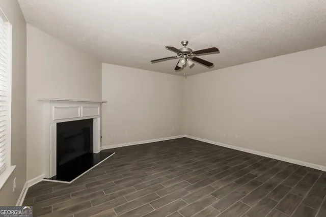a view of empty room with wooden floor and fireplace