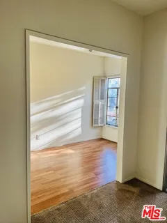 a view of an empty room with wooden floor and a window