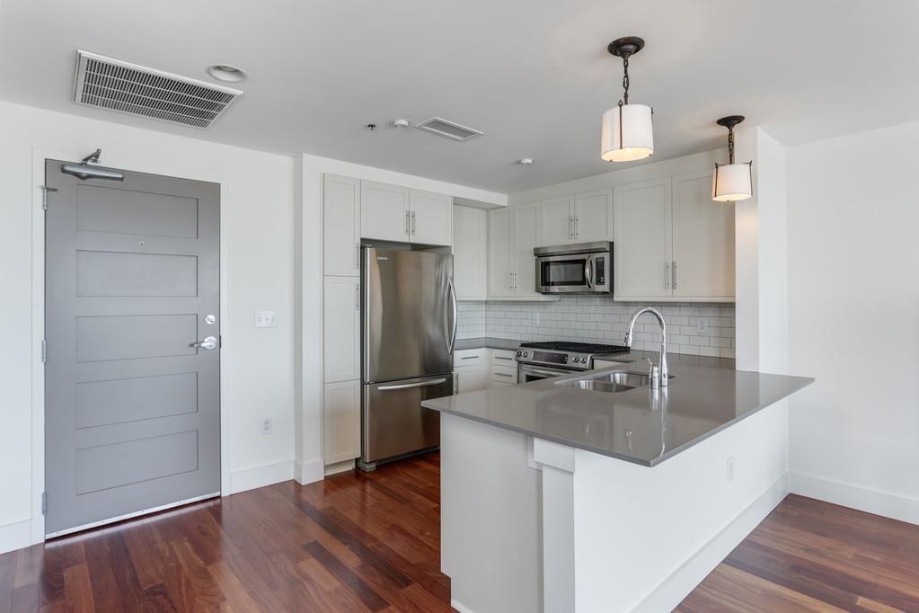 1100 Howell Mill Road Northwest, Unit 917 Atlanta, GA 30318 - Photo 4 of 22 a kitchen with granite countertop a refrigerator and a stove top oven
