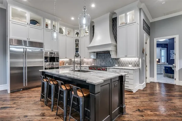a kitchen with stainless steel appliances granite countertop a table chairs stove and refrigerator