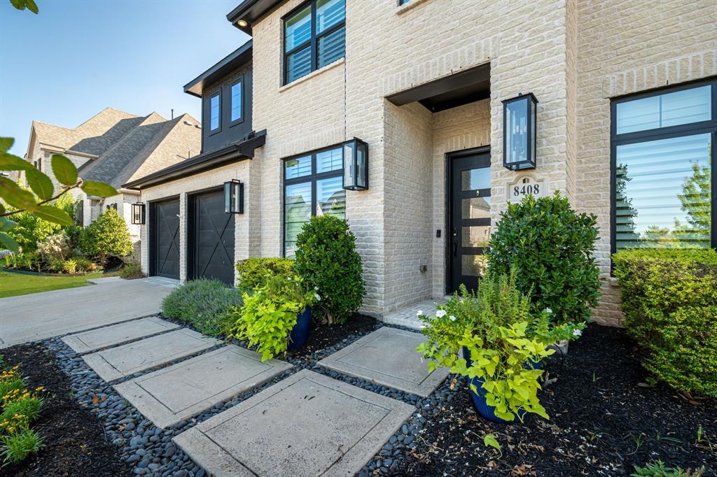 8408 Twistpine Road Frisco, TX 75035 - Photo 32 of 38 Light-colored brick facade with dark window frames, a contemporary front entry door, and a paver walkway