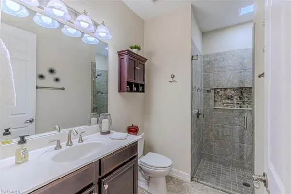 a bathroom with a sink vanity granite toilet and shower