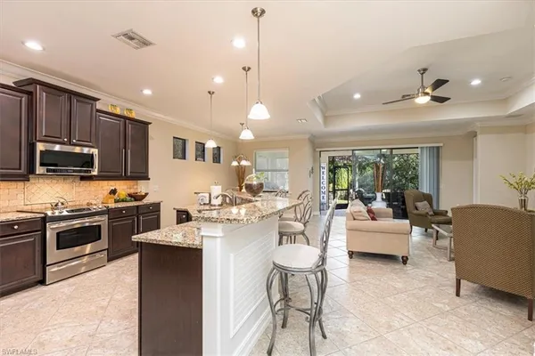 a large white kitchen with living room a stove a couch and a dining table with wooden floor