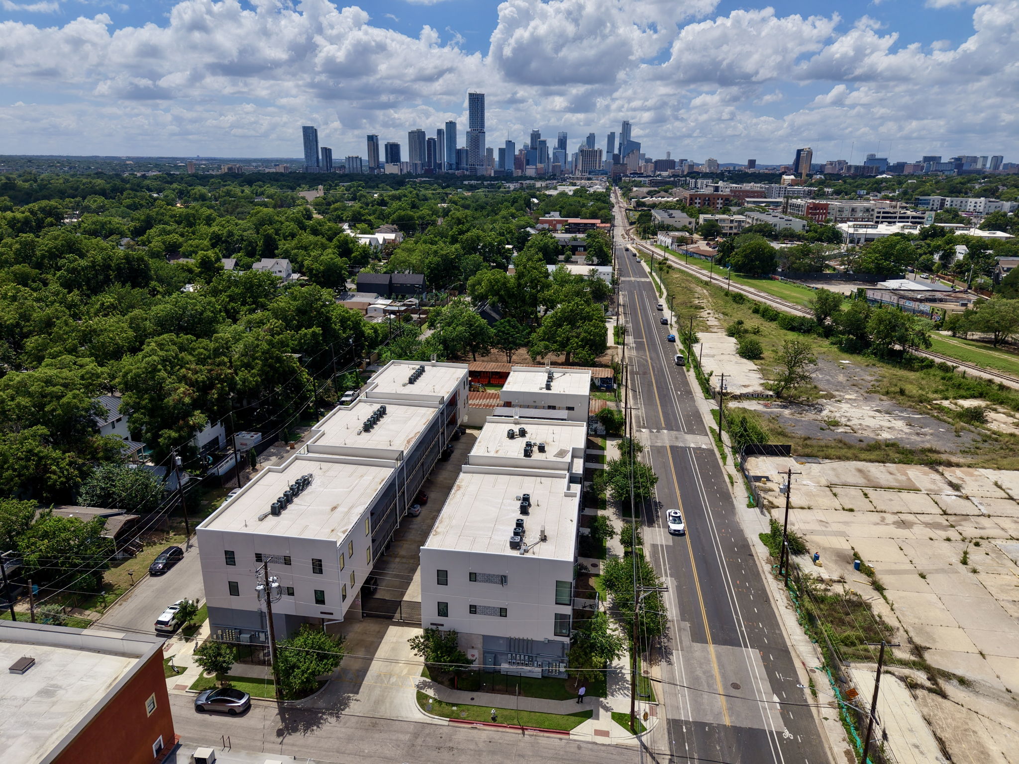 2709 East 5th Street, Unit 1306 Austin, TX 78702 - Photo 21 of 28 An aerial perspective reveals a vibrant city skyline towering over verdant surroundings and modern residential structures.