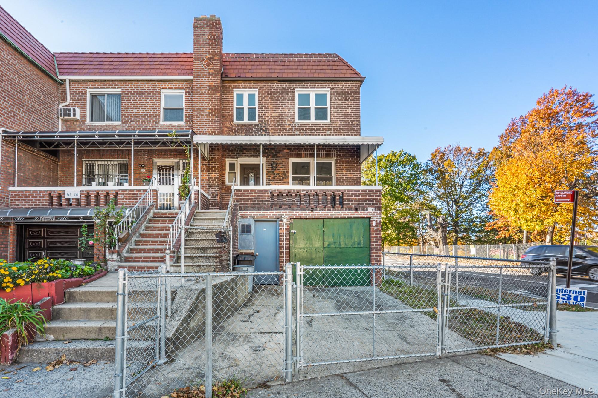 61-12 Main Street Queens, NY 11367 - Photo 1 of 35 View of front of property featuring a gate, brick siding, a fenced front yard, driveway, and a garage