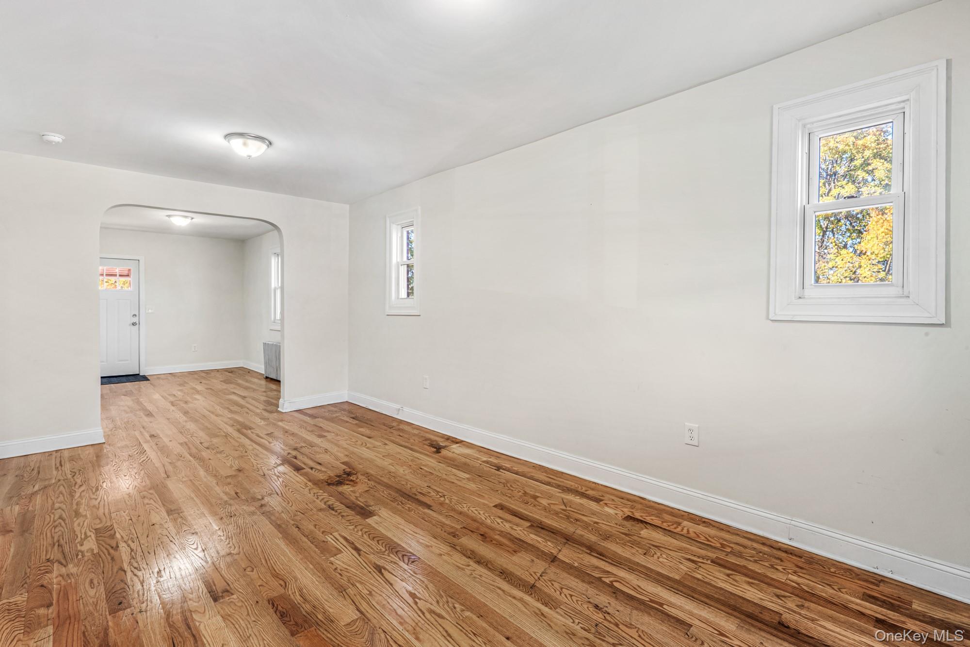 61-12 Main Street Queens, NY 11367 - Photo 16 of 35 Empty room with arched walkways, plenty of natural light, and light wood-style flooring