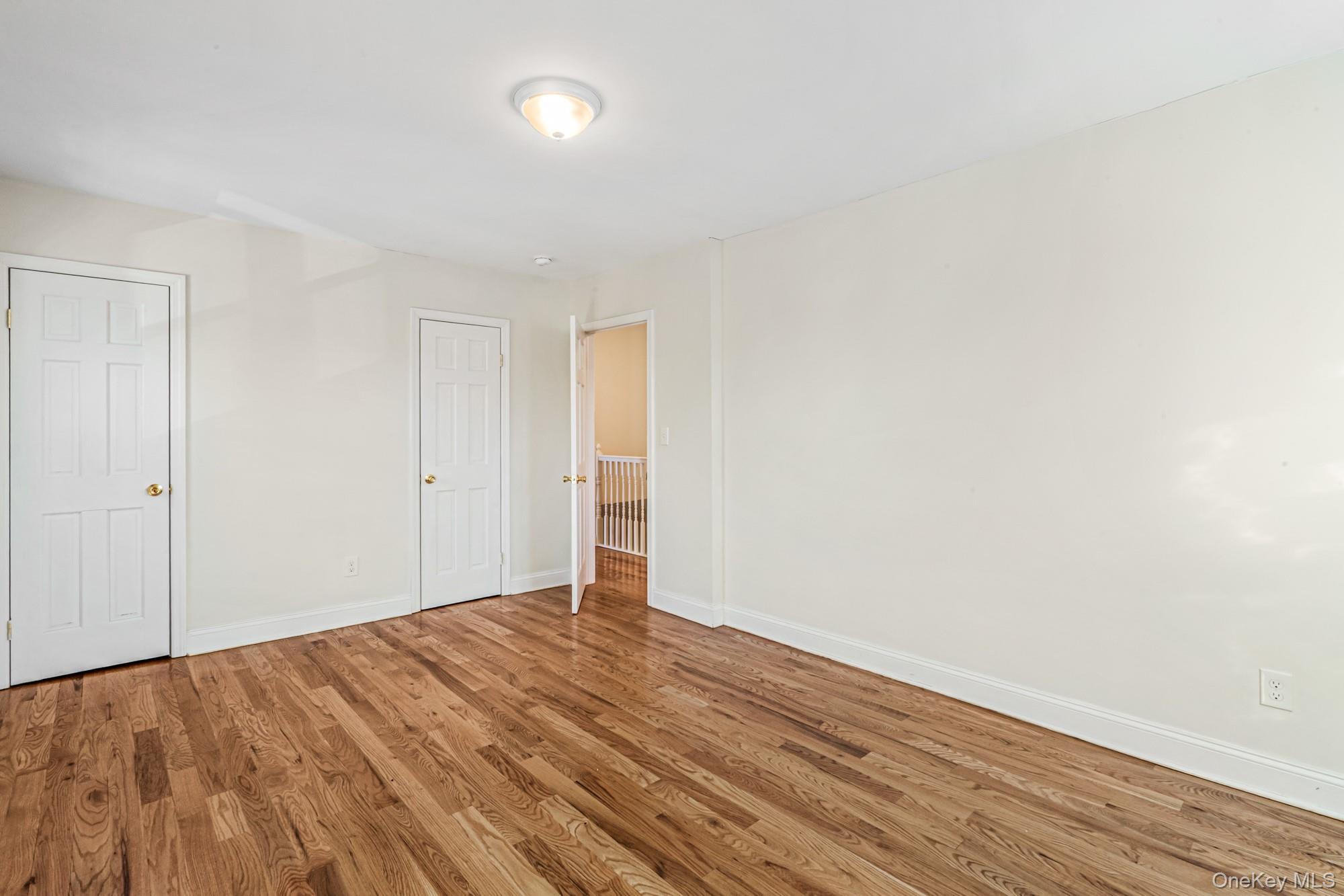 61-12 Main Street Queens, NY 11367 - Photo 25 of 35 Unfurnished bedroom with wood finished floors and baseboards