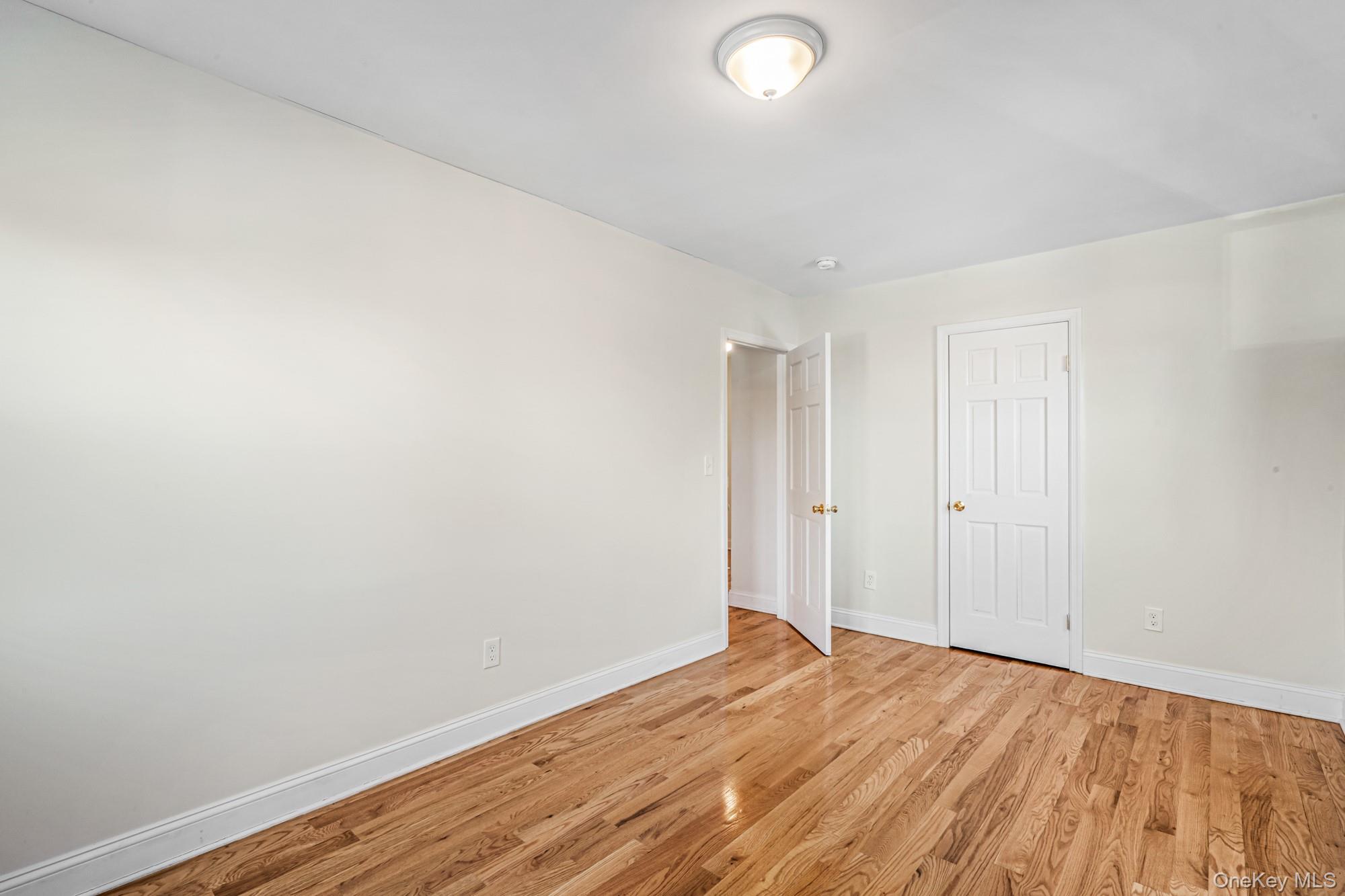 61-12 Main Street Queens, NY 11367 - Photo 26 of 35 Unfurnished bedroom with light wood-type flooring and baseboards