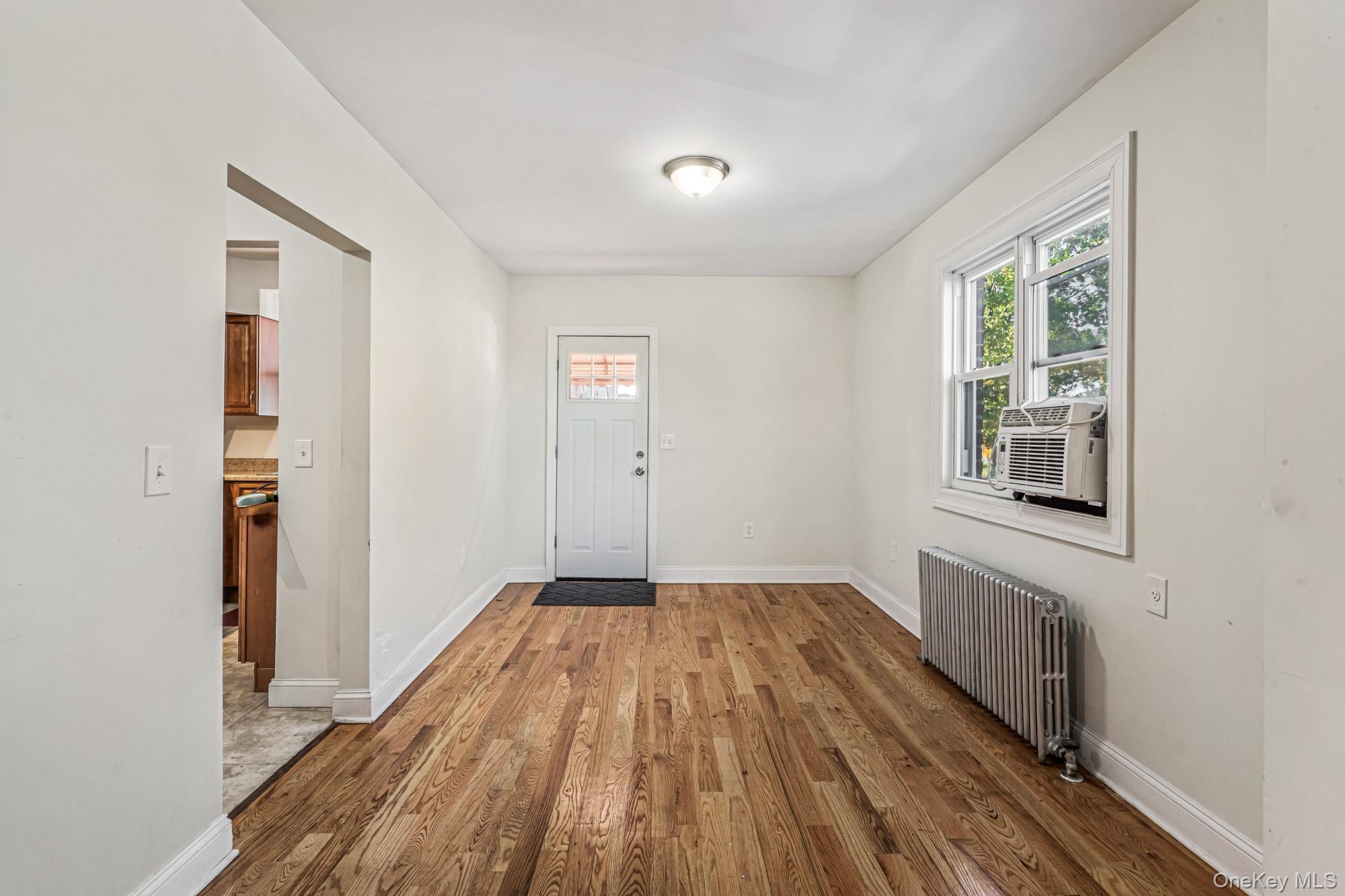 61-12 Main Street Queens, NY 11367 - Photo 5 of 35 Foyer entrance featuring radiator, wood finished floors, and cooling unit