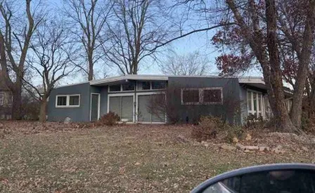 a front view of house with yard and trees in the background