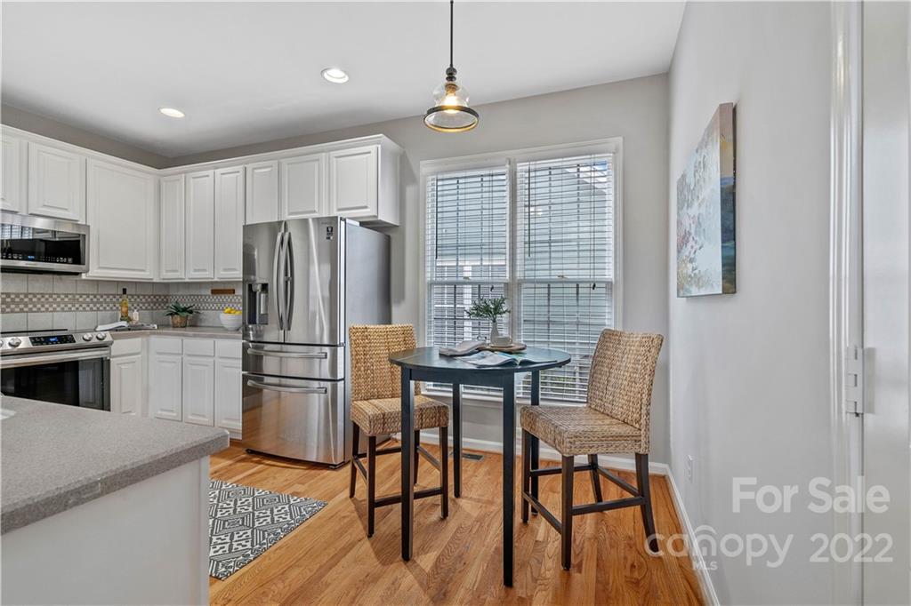 412 Third Baxter Street Fort Mill, SC 29708 - Photo 12 of 39 a kitchen with stainless steel appliances granite countertop a refrigerator a stove a sink dishwasher a dining table and chairs with wooden floor