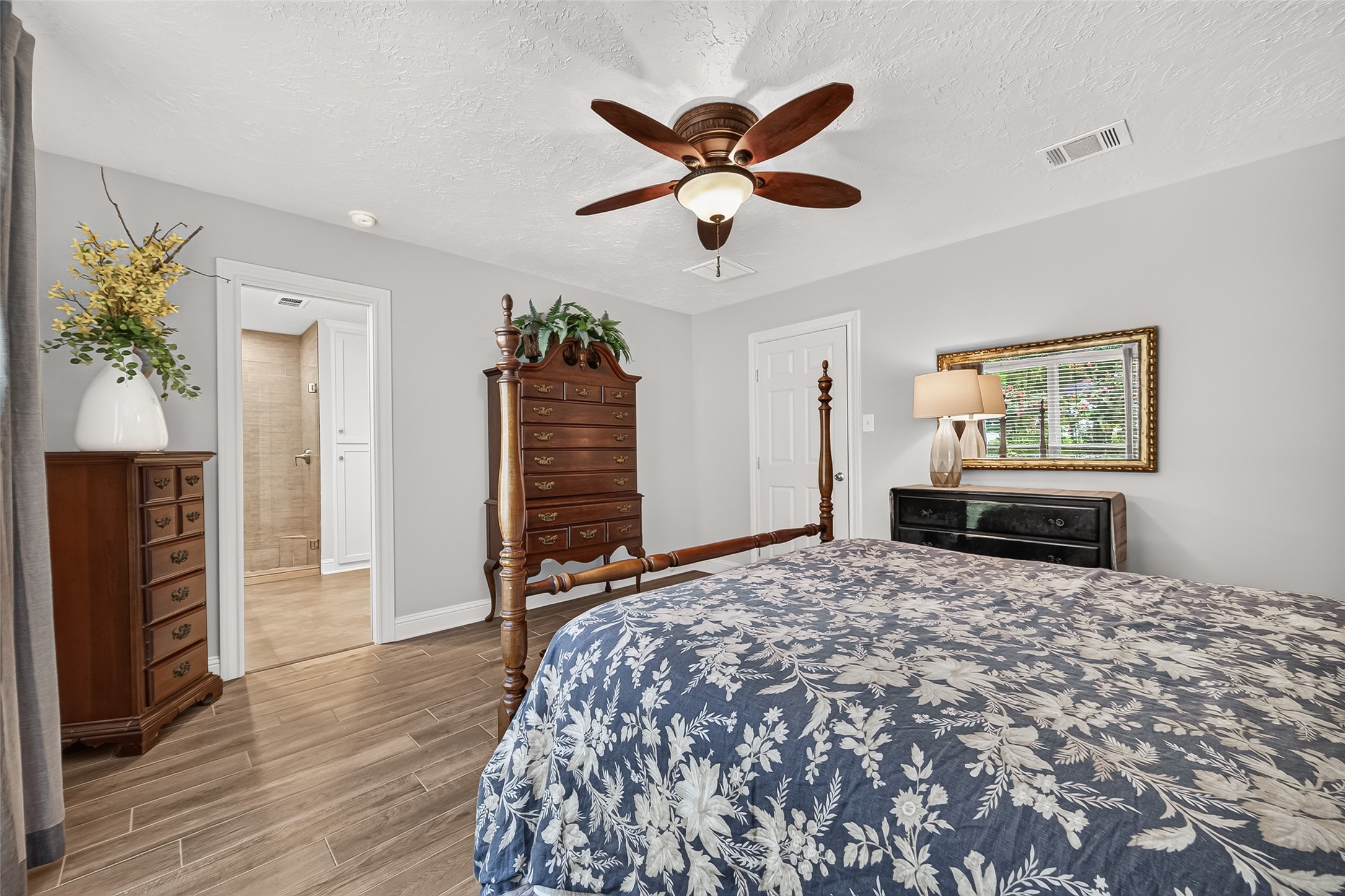 24719 Wilderness Road Spring, TX 77380 - Photo 28 of 42 This spacious primary bedroom features elegant ceramic tile flooring, a stylish ceiling fan, and ample natural light from large windows with blinds.