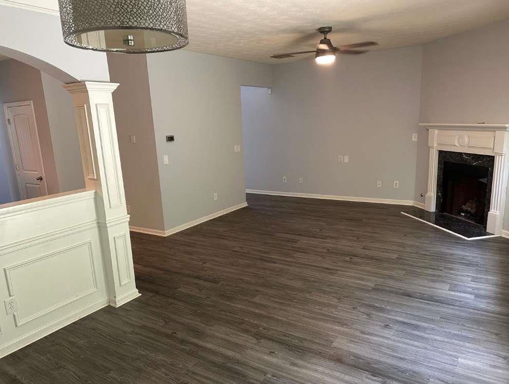 5103 Jack Drive Decatur, GA 30035 - Photo 5 of 34 an empty room with wooden floor a ceiling fan a kitchen view and a fireplace