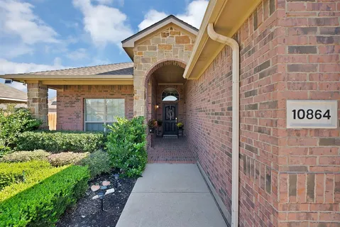 a view of a brick house with potted plants next to a yard