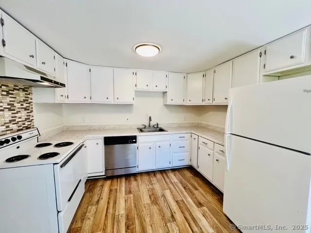 a kitchen with cabinets appliances wooden floor and a window