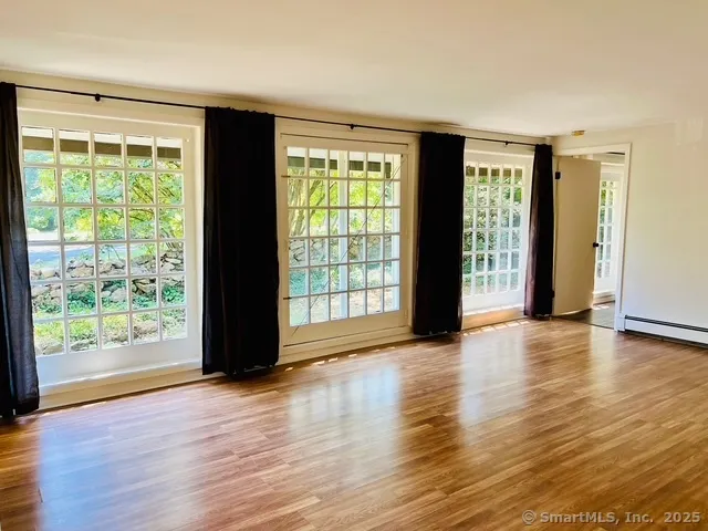 a view of an empty room with wooden floor and a window