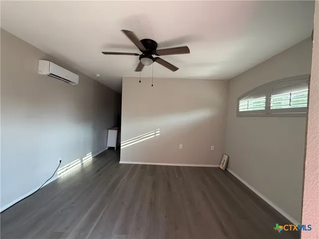 an empty room with wooden floor fan and windows