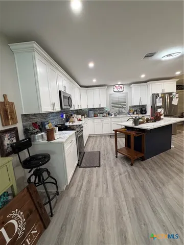 a kitchen with stainless steel appliances kitchen island granite countertop a stove refrigerator and cabinets