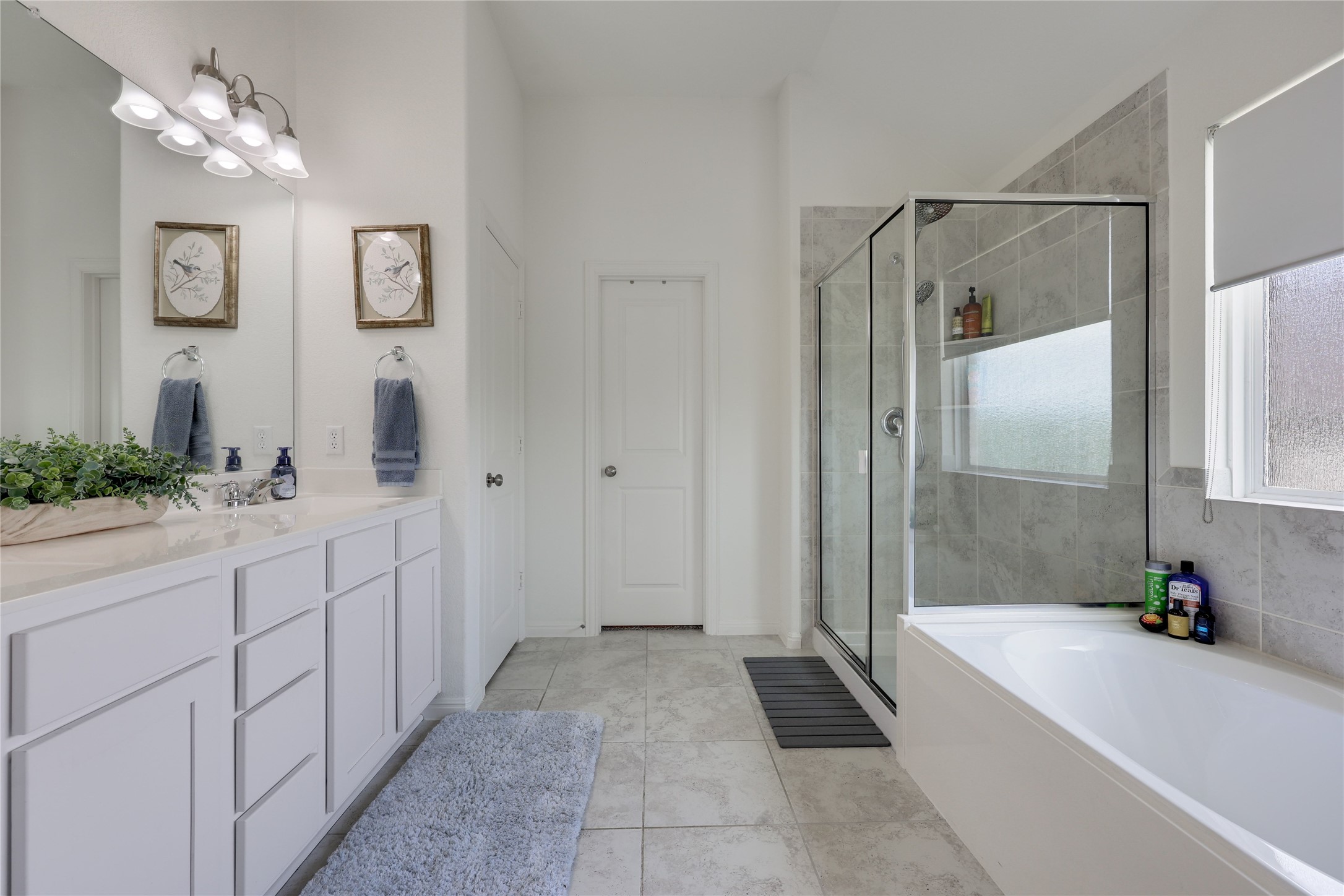 240 Prato Place Georgetown, TX 78628 - Photo 20 of 40 The bathroom features a double vanity with ample storage, a glass-enclosed shower, and a separate bathtub