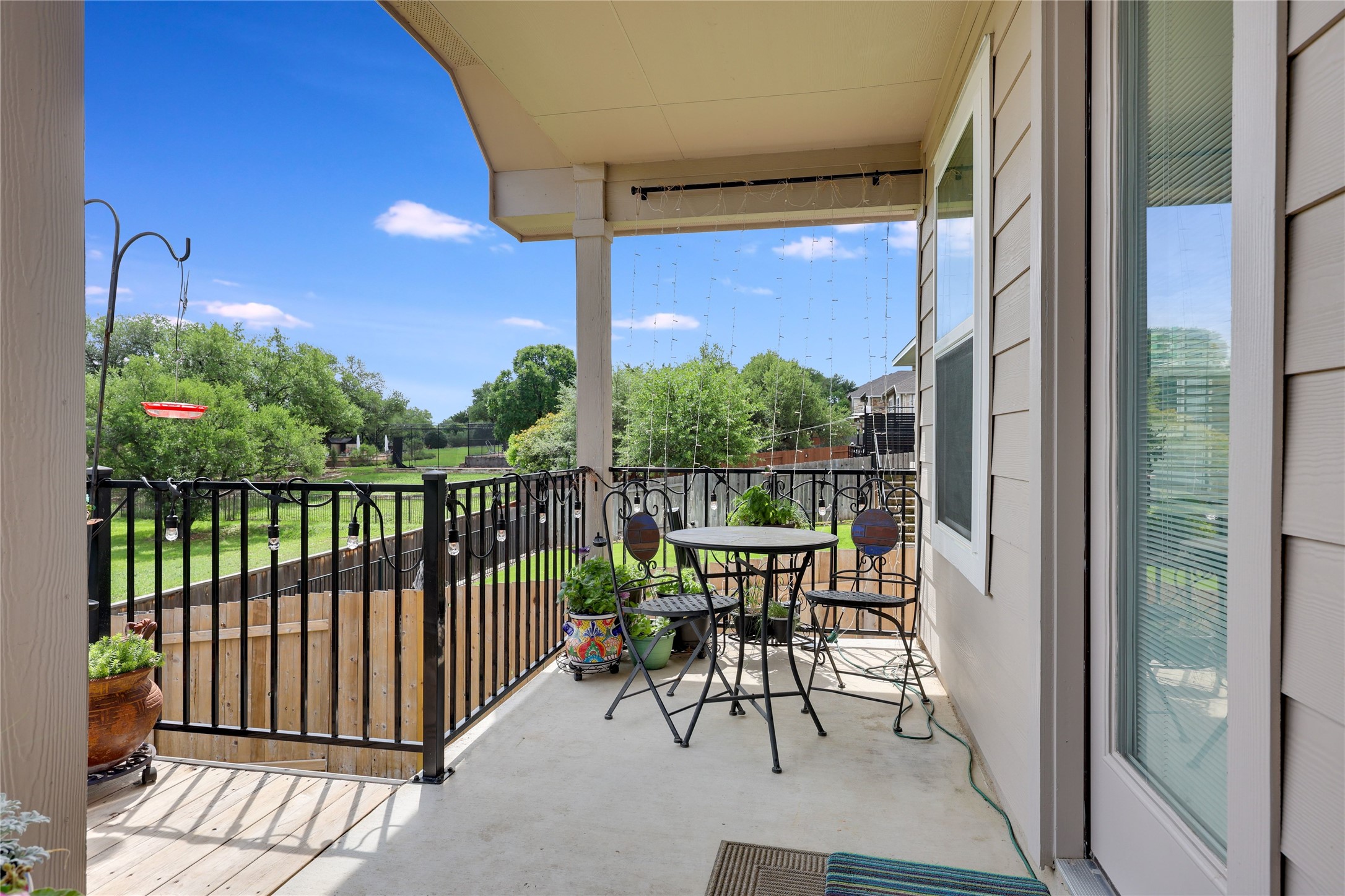 240 Prato Place Georgetown, TX 78628 - Photo 31 of 40 The property features a covered patio with a concrete floor and a black metal railing, offering views of a landscaped yard with trees
