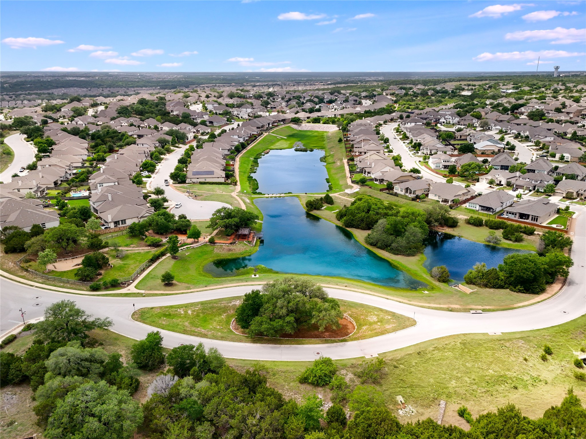 240 Prato Place Georgetown, TX 78628 - Photo 39 of 40 An aerial view showcasing the established neighborhood with curved streets, numerous homes with grey roofs, and a series of interconnected bodies of water