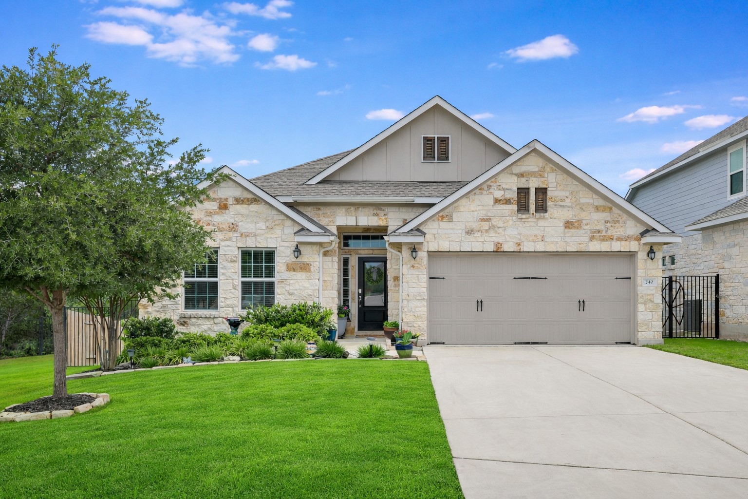 240 Prato Place Georgetown, TX 78628 - Photo 40 of 40 The property features an attractive stone exterior, a well-maintained lawn, and a paved driveway leading to a two-car garage. Grass-AI enhanced