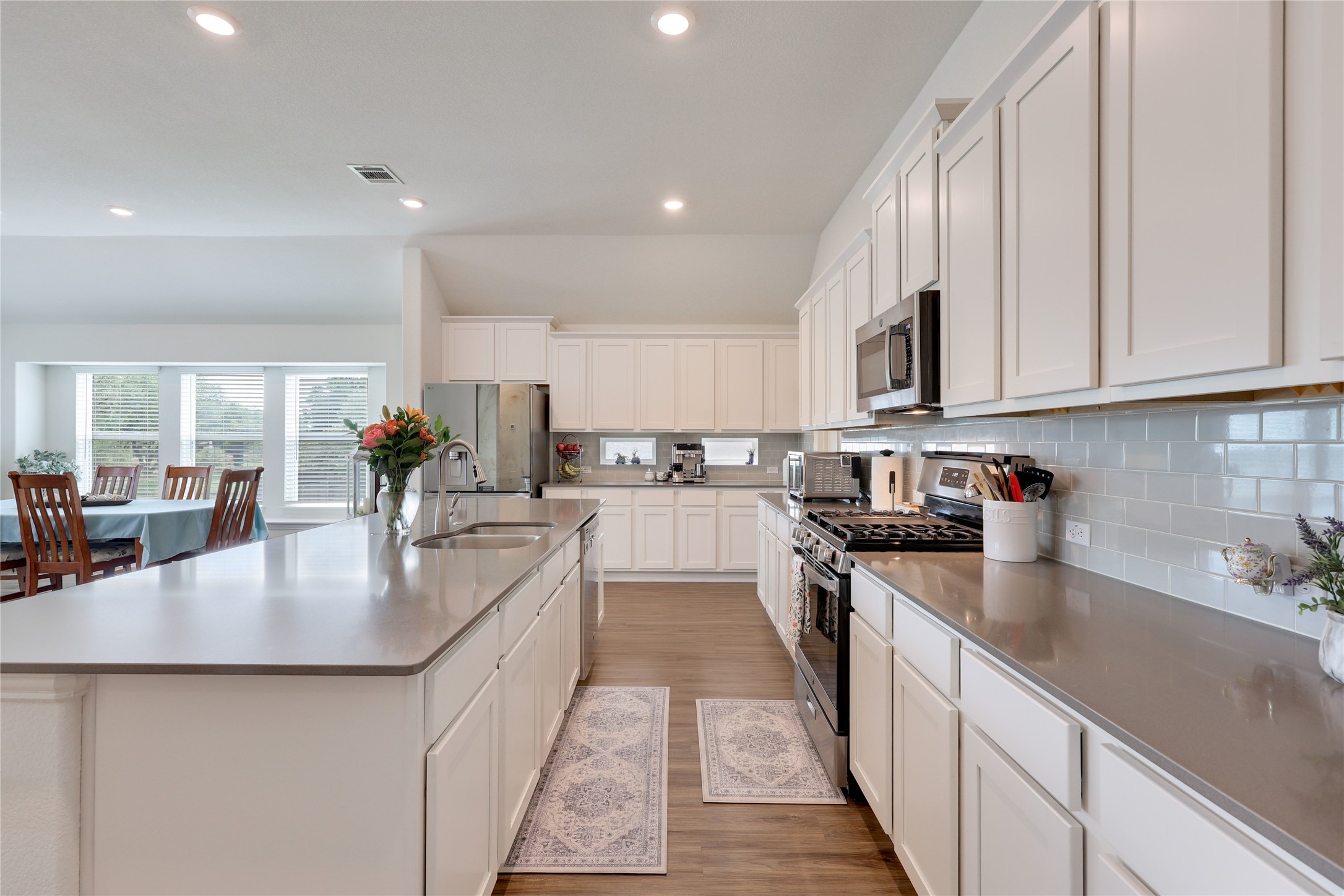 240 Prato Place Georgetown, TX 78628 - Photo 8 of 40 The spacious kitchen features an expansive island with a double sink, white cabinetry, a subway tile backsplash, and stainless steel appliances