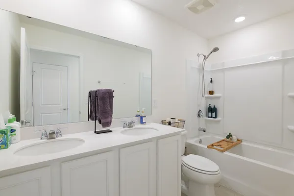 a bathroom with a double vanity sink toilet mirror and shower