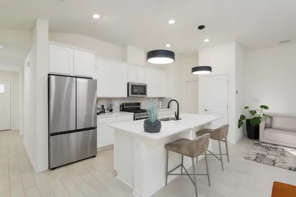 a kitchen with stainless steel appliances granite countertop a refrigerator a sink a stove a dining table and chairs