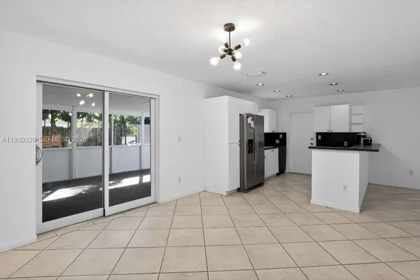 a view of a kitchen with fridge and an empty room
