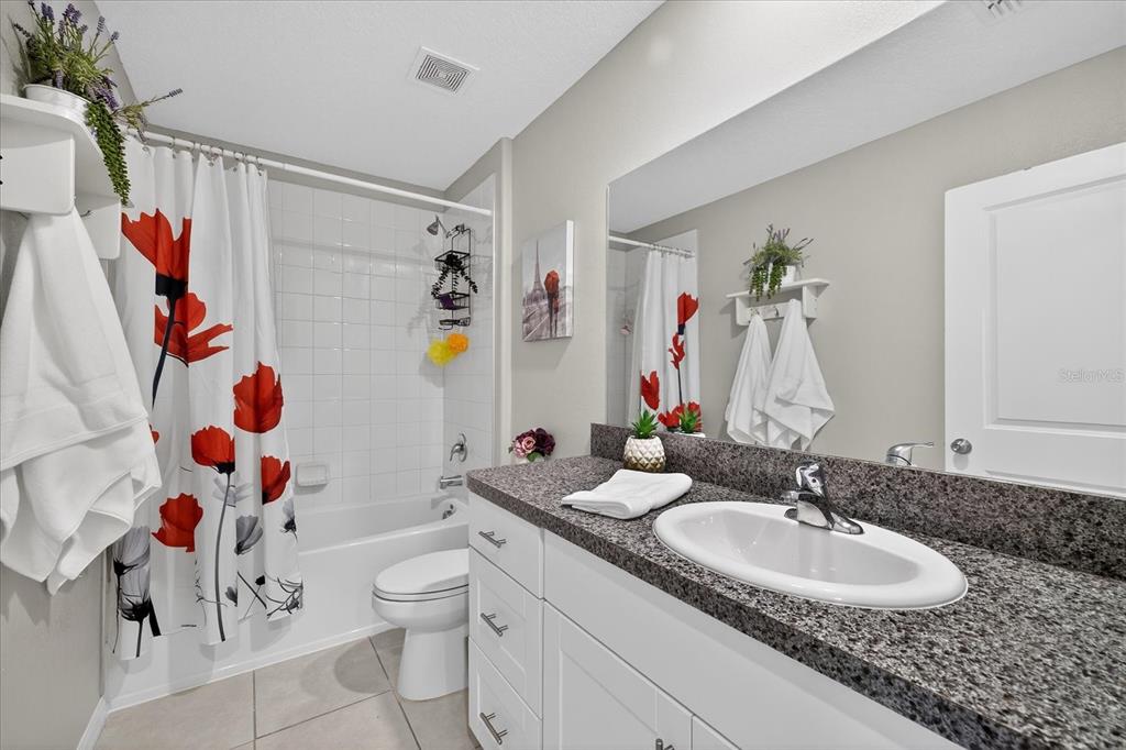 6115 Apple Snail Avenue New Port Richey, FL 34653 - Photo 22 of 59 a bathroom with a granite countertop sink a toilet and a mirror