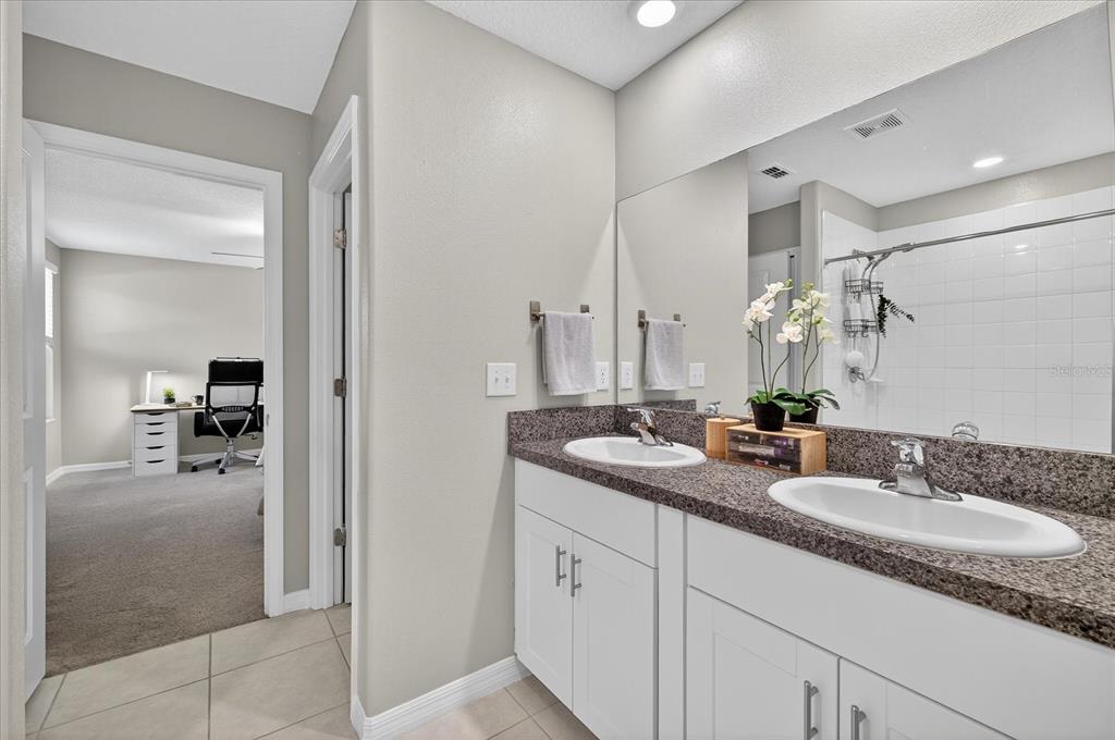 6115 Apple Snail Avenue New Port Richey, FL 34653 - Photo 38 of 59 a en suite bathroom with double sink and a mirror