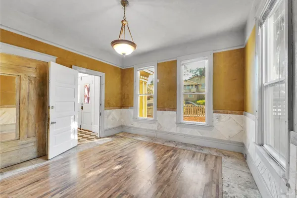 a view of an empty room with a window and wooden floor