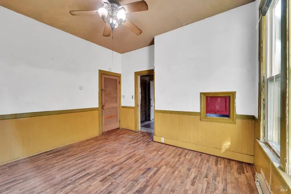a view of a room with wooden floor and a ceiling fan