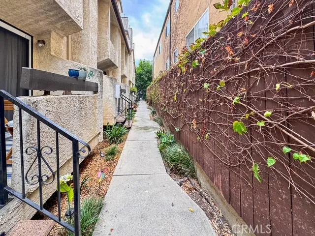 a pathway of a house with a yard and potted plants