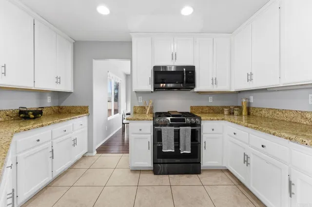 a kitchen with stainless steel appliances granite countertop a stove a sink a microwave a refrigerator and cabinets
