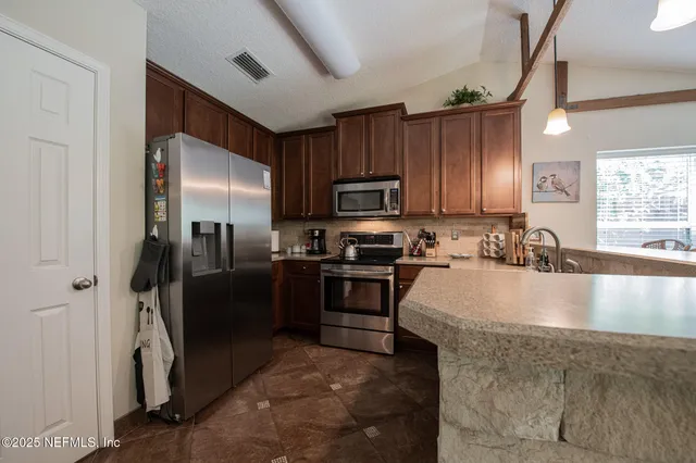 a modern kitchen with stainless steel appliances granite countertop a refrigerator a stove a sink and a microwave