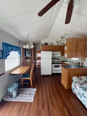a kitchen with stainless steel appliances kitchen island granite countertop a table chairs and a wooden floor