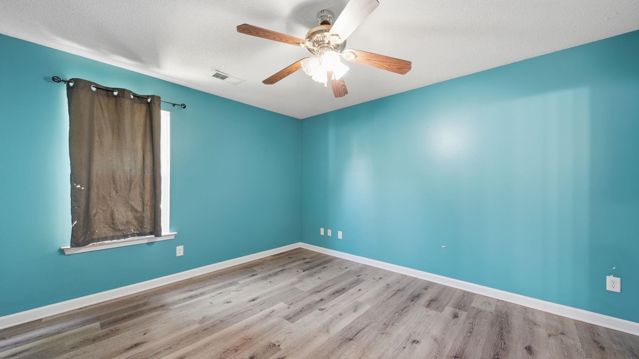 217 Rae Drive Munford, TN 38058 - Photo 18 of 40 Spacious bedroom room featuring wood-finish flooring, a ceiling fan with integrated lighting, and a single window with white trim.