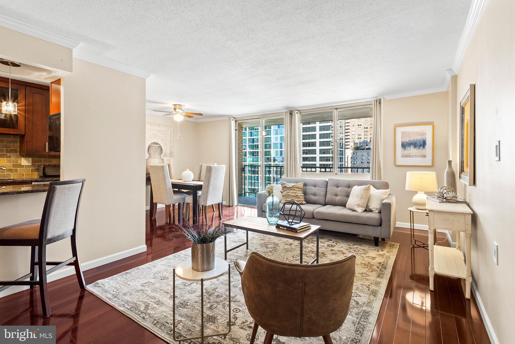 a living room with furniture large windows and wooden floor