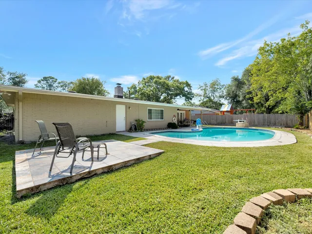 a view of a swimming pool with lawn chairs under an umbrella