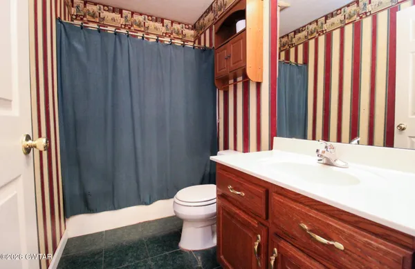 a bathroom with a sink a toilet and shower curtain