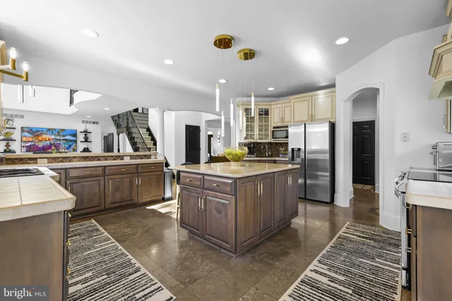 a kitchen with stainless steel appliances kitchen island granite countertop a refrigerator a stove a sink dishwasher and white cabinets with wooden floor