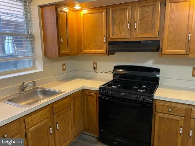 a kitchen with granite countertop wood cabinets and a stove top oven
